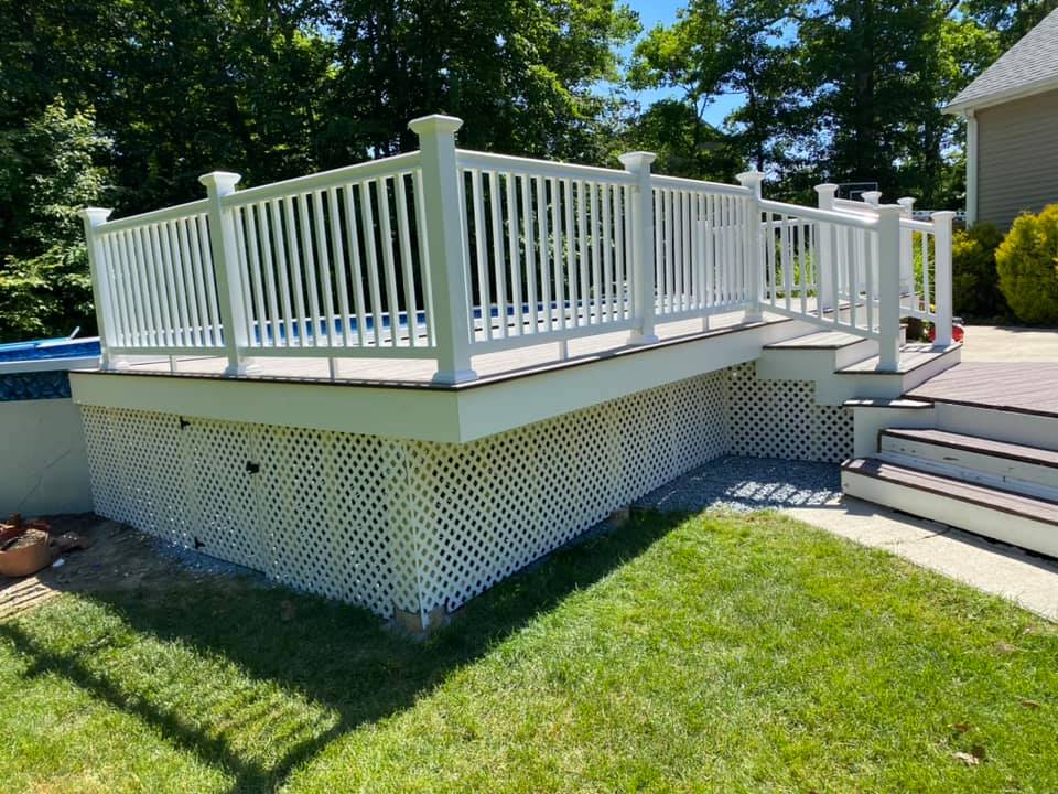 Finished pool surround deck and stairs with white under deck storage, white railing an brown surface