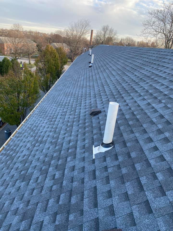 Gray asphalt shingle roofing installed around small chimney pipes
